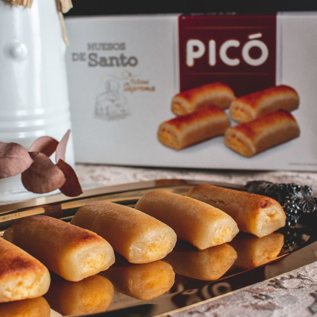 Huesos de santo de mazapán rellenos de yema en una bandeja, con su caja Picó al fondo