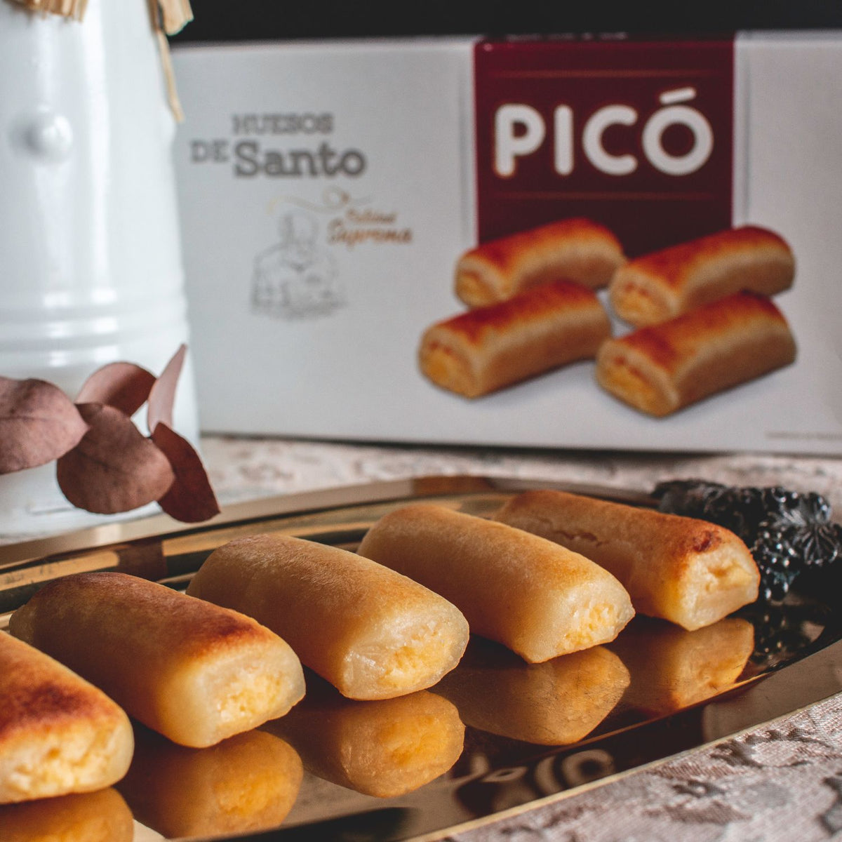 Huesos de santo de mazapán rellenos de yema en una bandeja, con su caja Picó al fondo