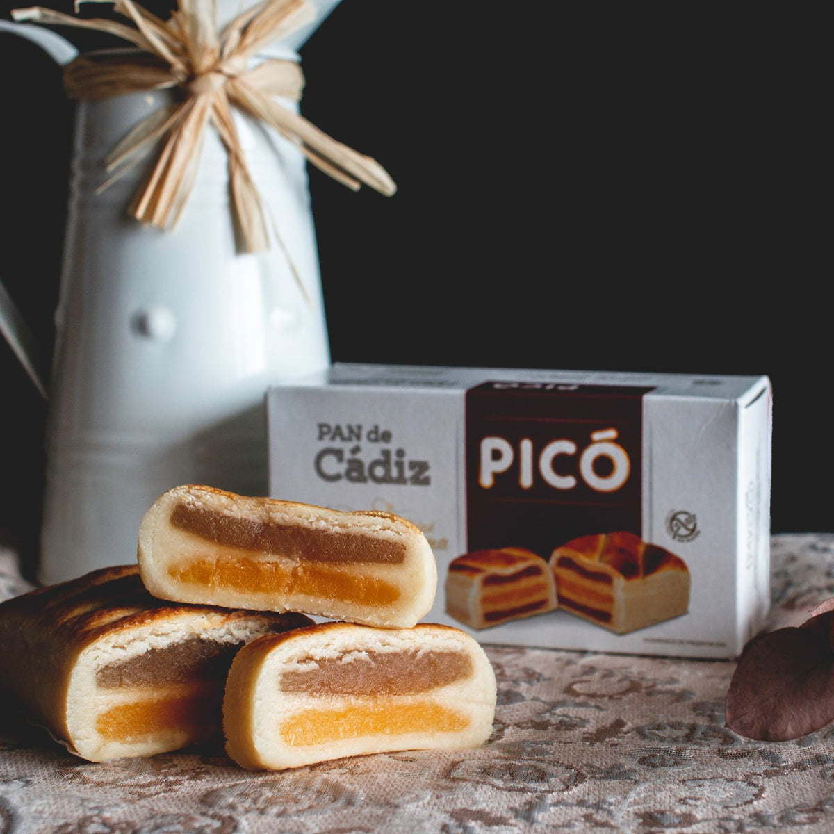 Pan de Cádiz cortado, con capas de mazapán y relleno de yema y cabello de ángel, junto a su caja Picó