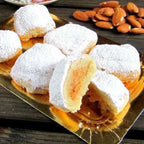 Pasteles de yema con azúcar glas, uno partido por la mitad, con almendras al lado