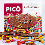 Torta de chocolate crujiente con Picolatinas de colores partida sobre un lecho de grageas, con la caja Picó