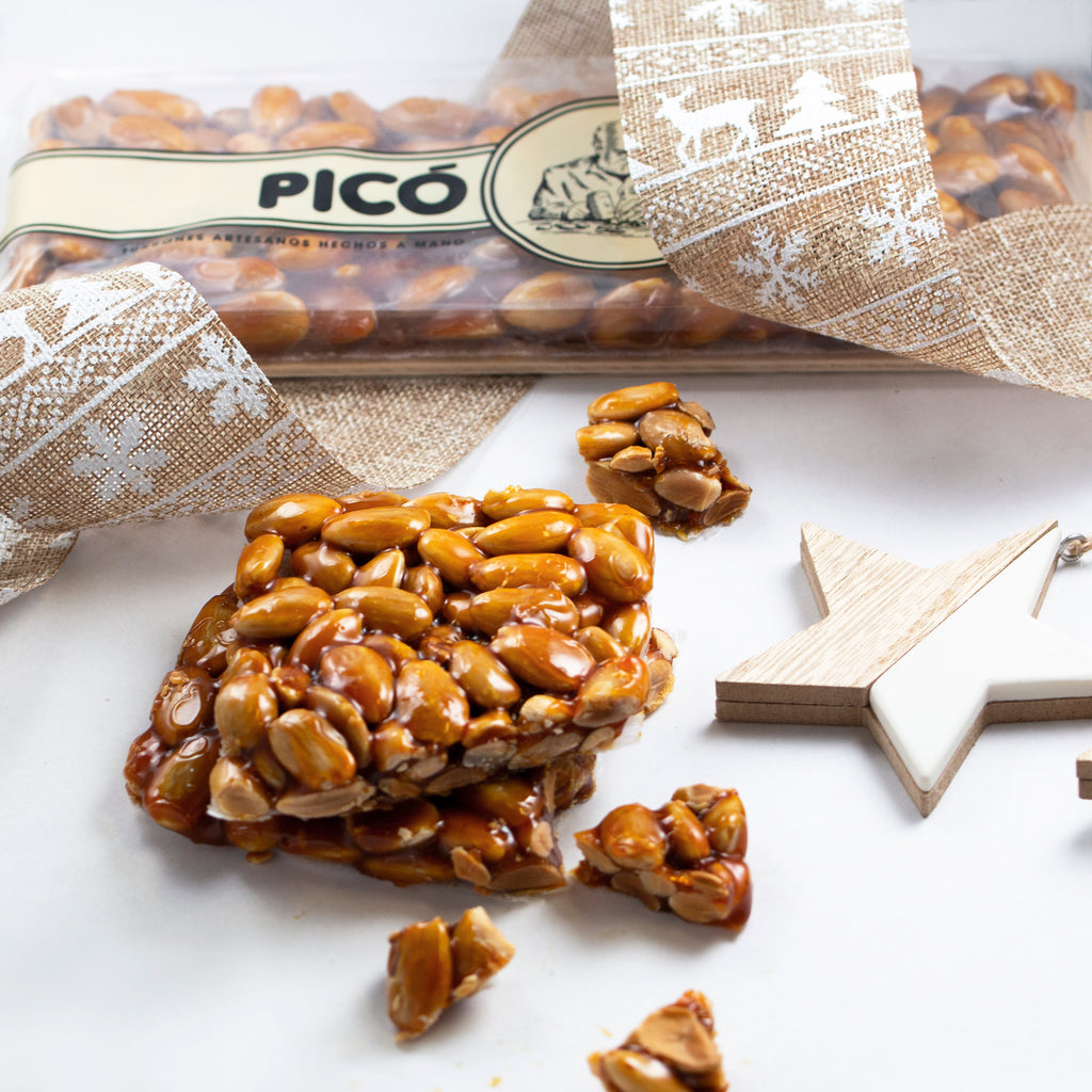 Trozo de turrón de cristal con almendras caramelizadas, con su envase Picó y una estrella de madera