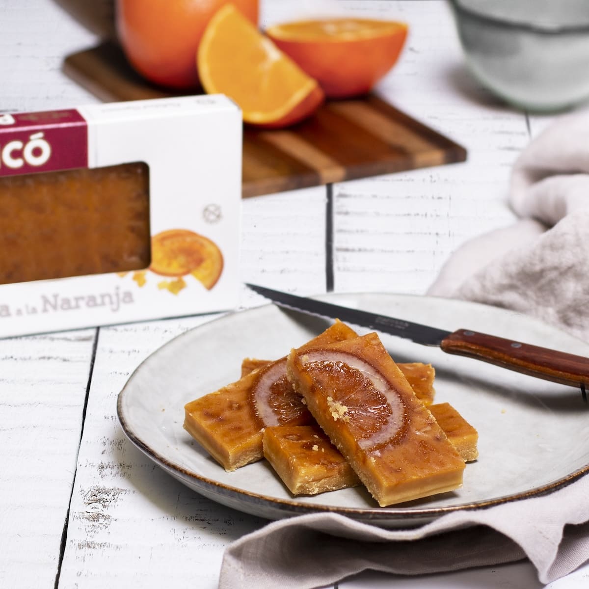 Barritas de turrón de yema a la naranja en un plato, con naranjas y la caja Picó