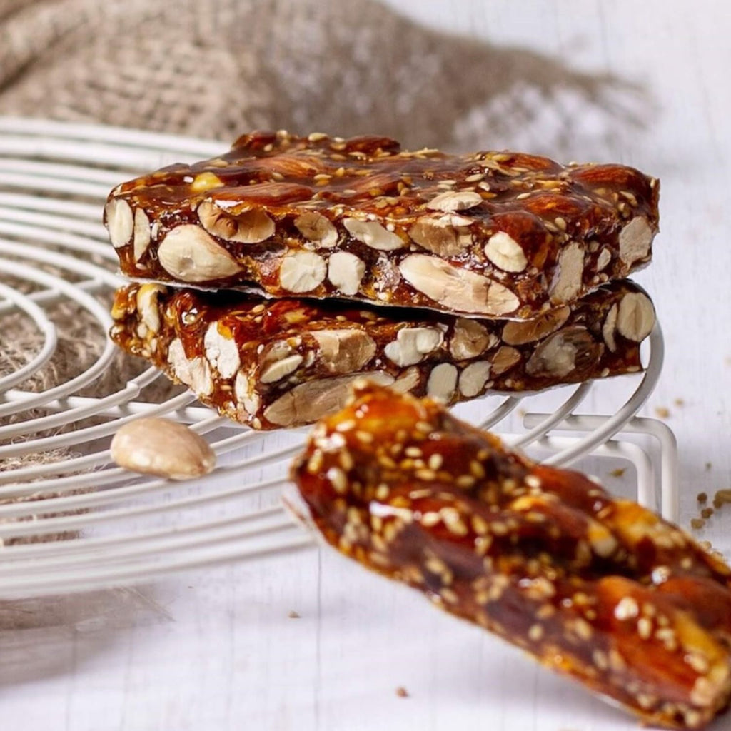 Trozos de turrón de guirlache con almendras y ajonjolí apilados sobre una rejilla