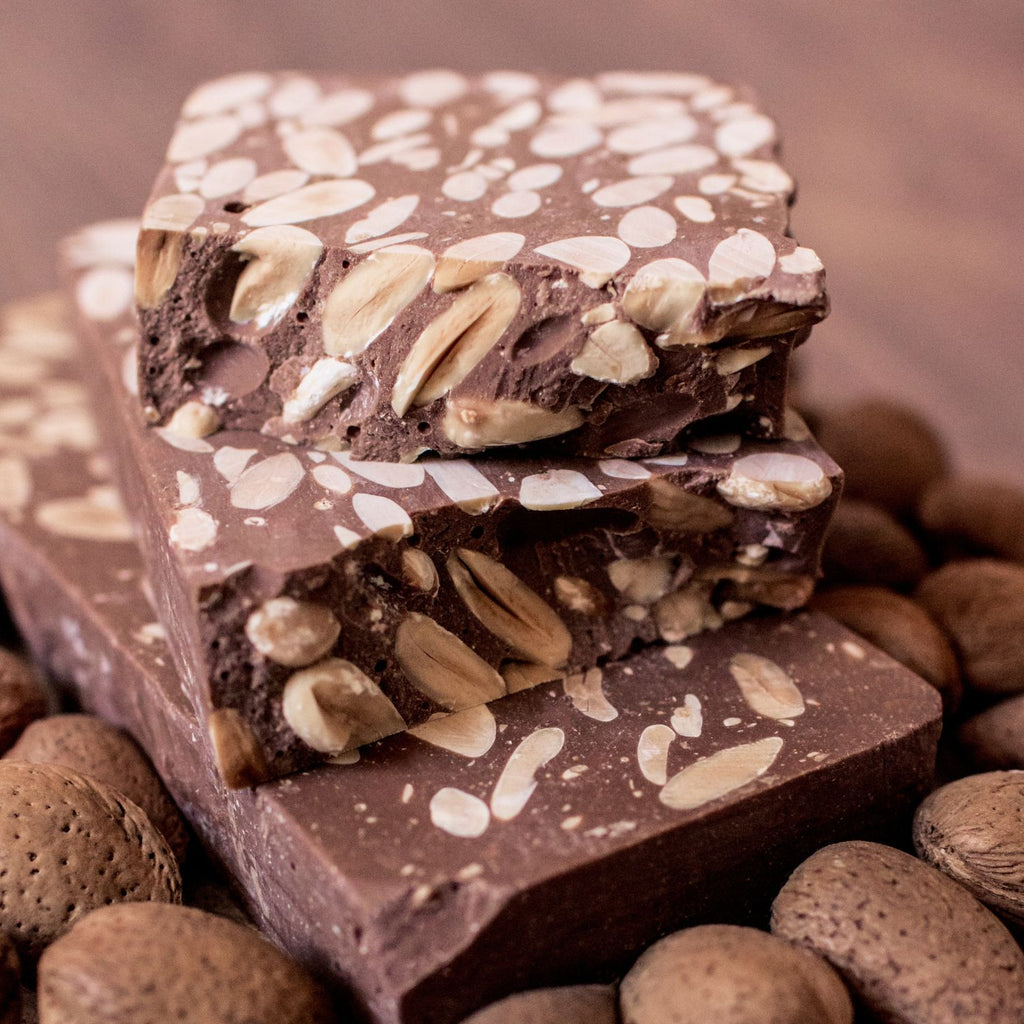 Turrón de chocolate con almendras enteras cortado en bloques, con almendras con cáscara