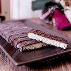 Turrón de coco bañado en chocolate cortado, mostrando el interior blanco de coco