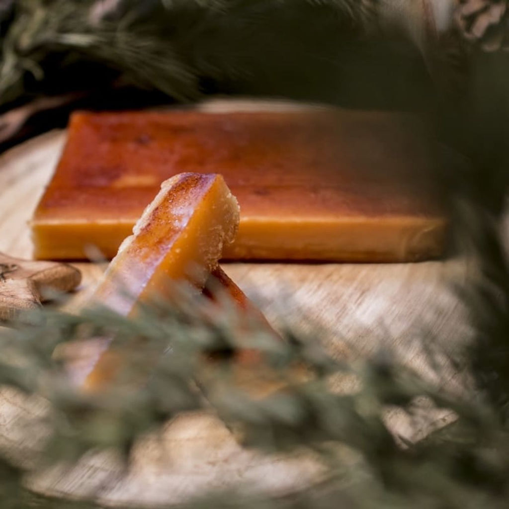 Turrón de yema tostada con la superficie caramelizada, cortado sobre una tabla con ramas de abeto