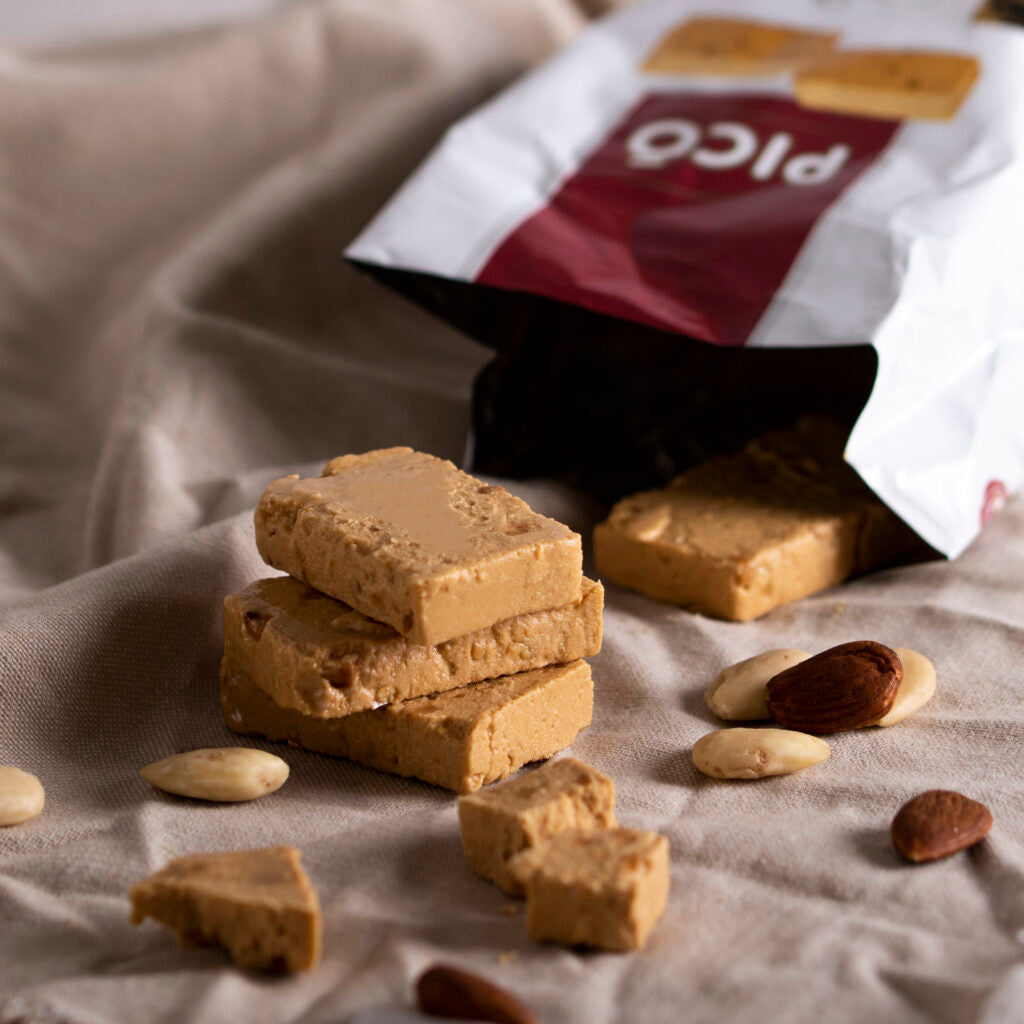 Porciones de turrón de Jijona apiladas saliendo de su bolsa, con almendras