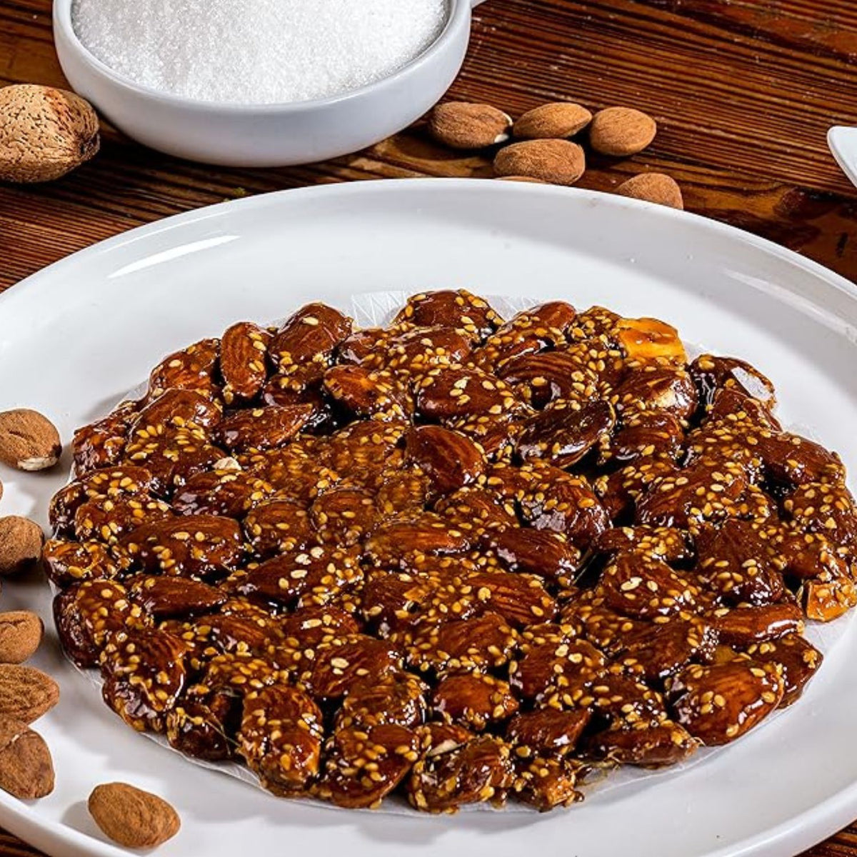 Torta de guirlache con almendras y ajonjolí en un plato, con almendras alrededor