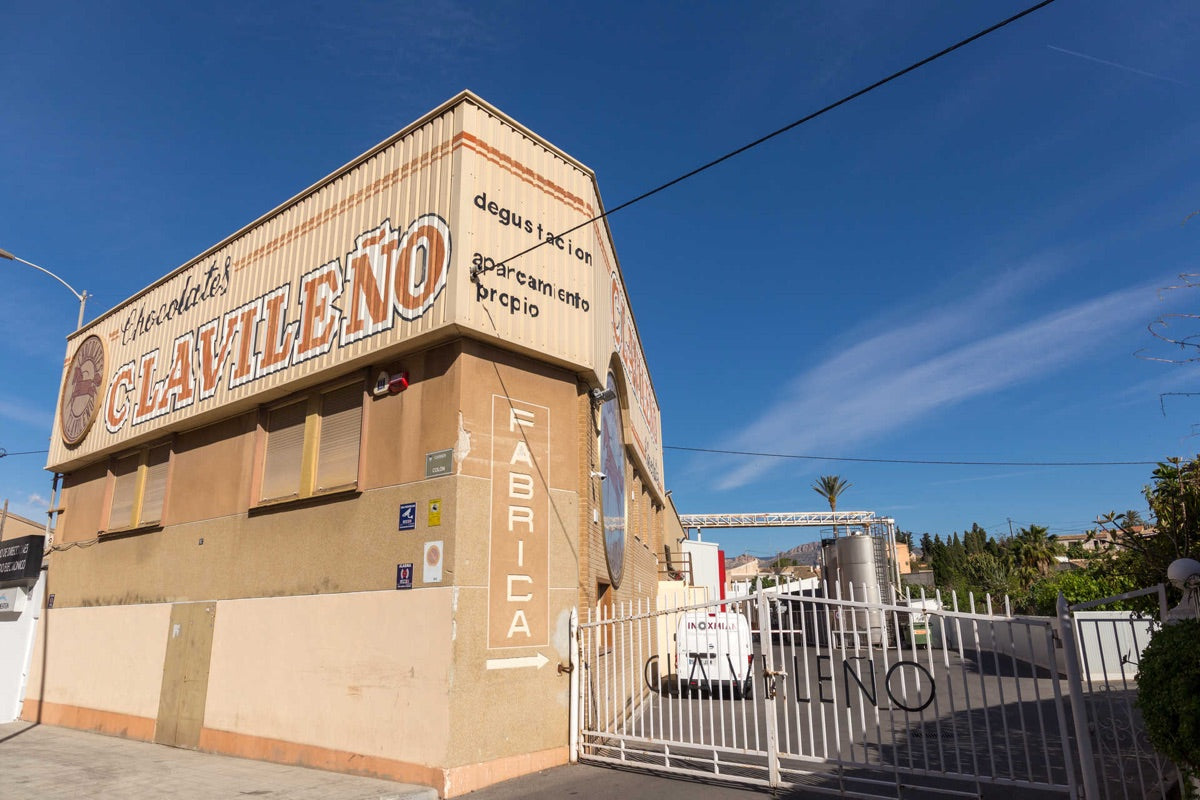 Fachada de la fábrica de Chocolates Clavileño, con el rótulo pintado en la esquina y la verja de entrada