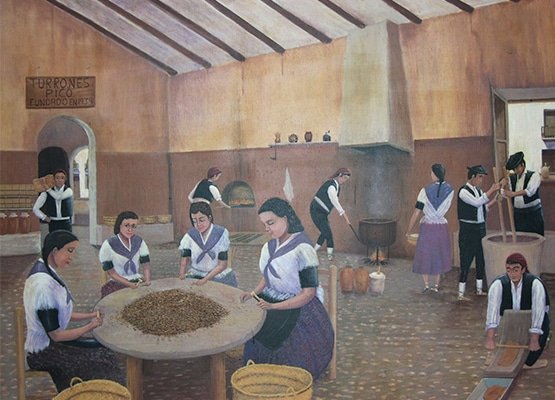 Pintura del obrador original de Turrones Picó: mujeres pelando almendra alrededor de una mesa y hombres picando en el mortero